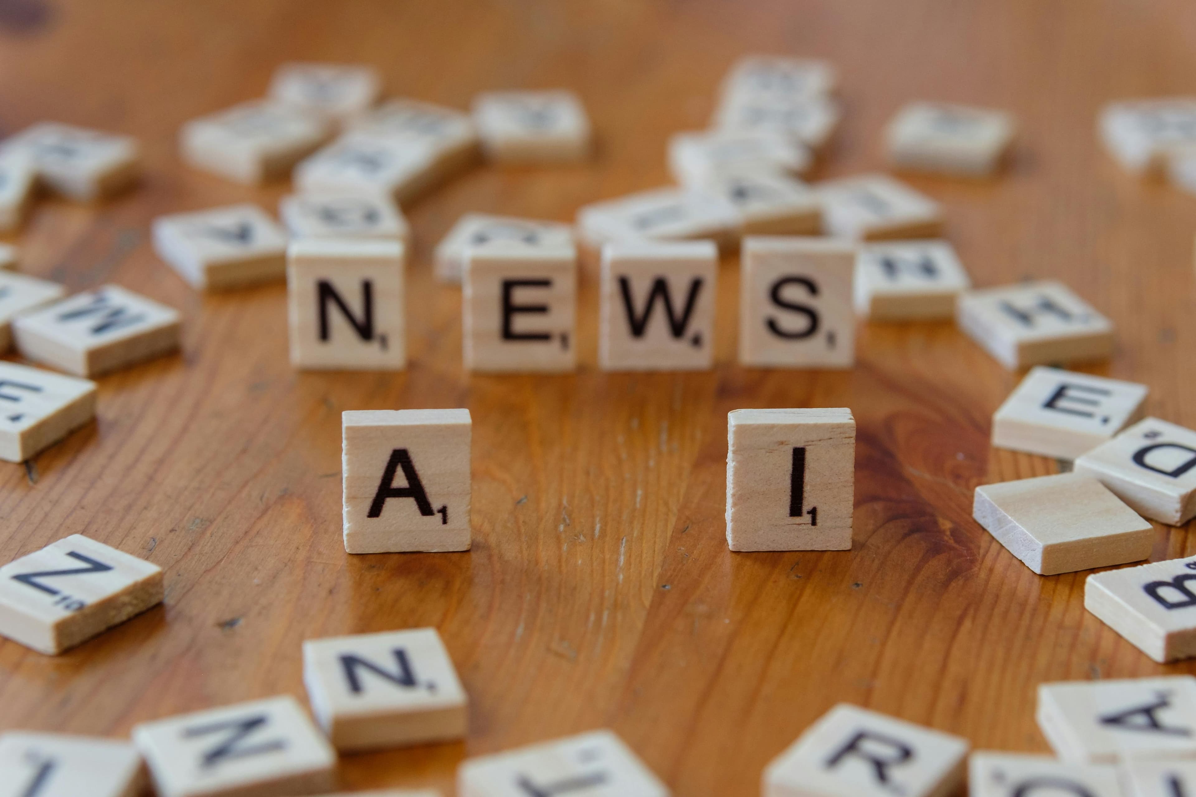 Bir teknoloji konsepti görseli için 'AI' ve 'NEWS' yazan ahşap scrabble harfleri.