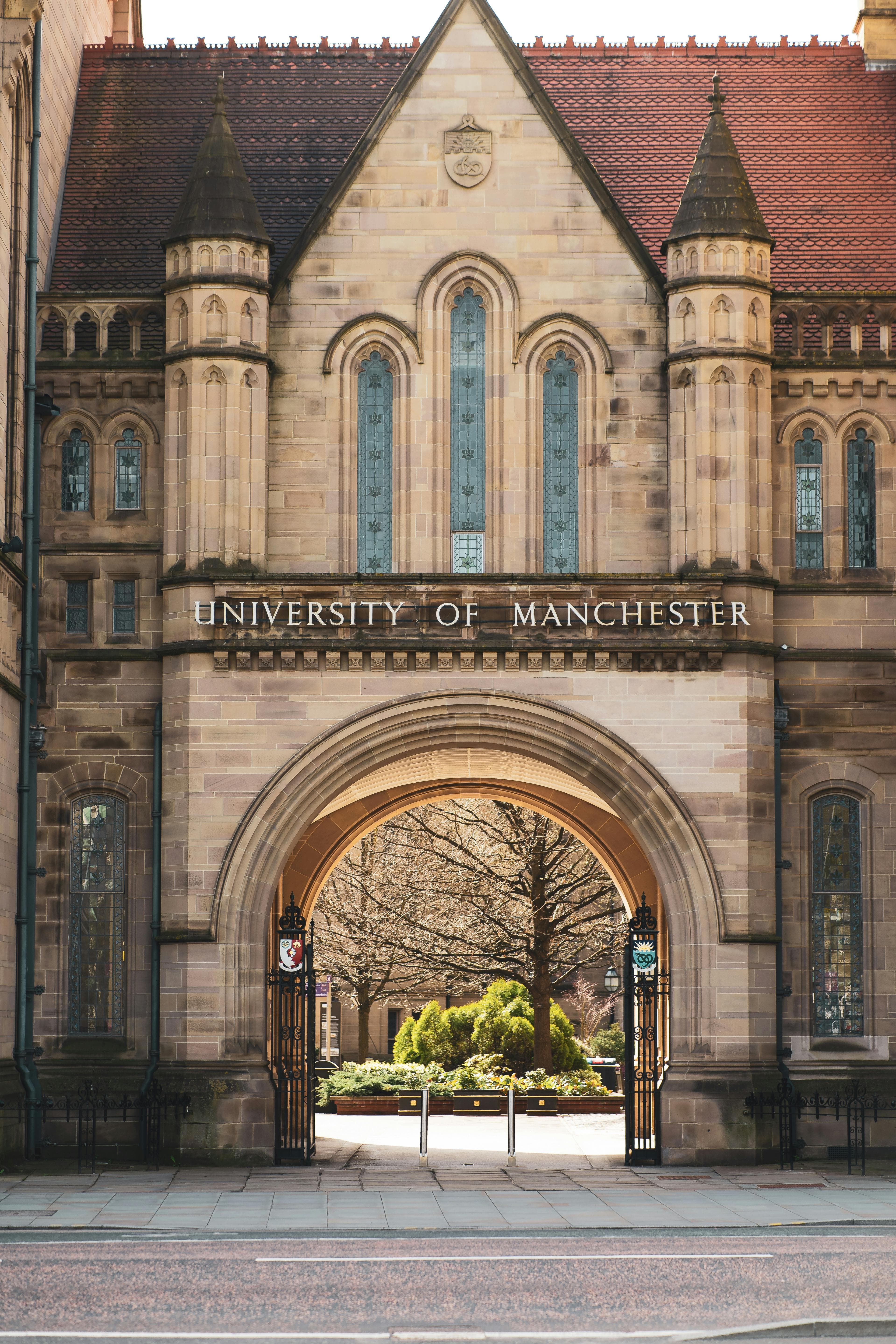 Historic entrance arch at the University of Manchester in England, showcasing gothic architecture.
