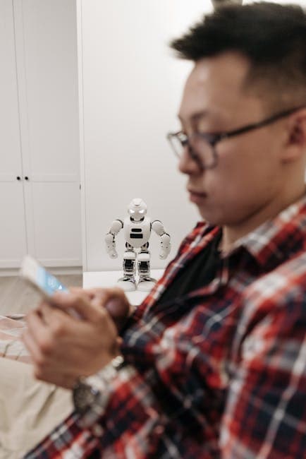 Man focused on smartphone with robot in background, depicting modern technology.