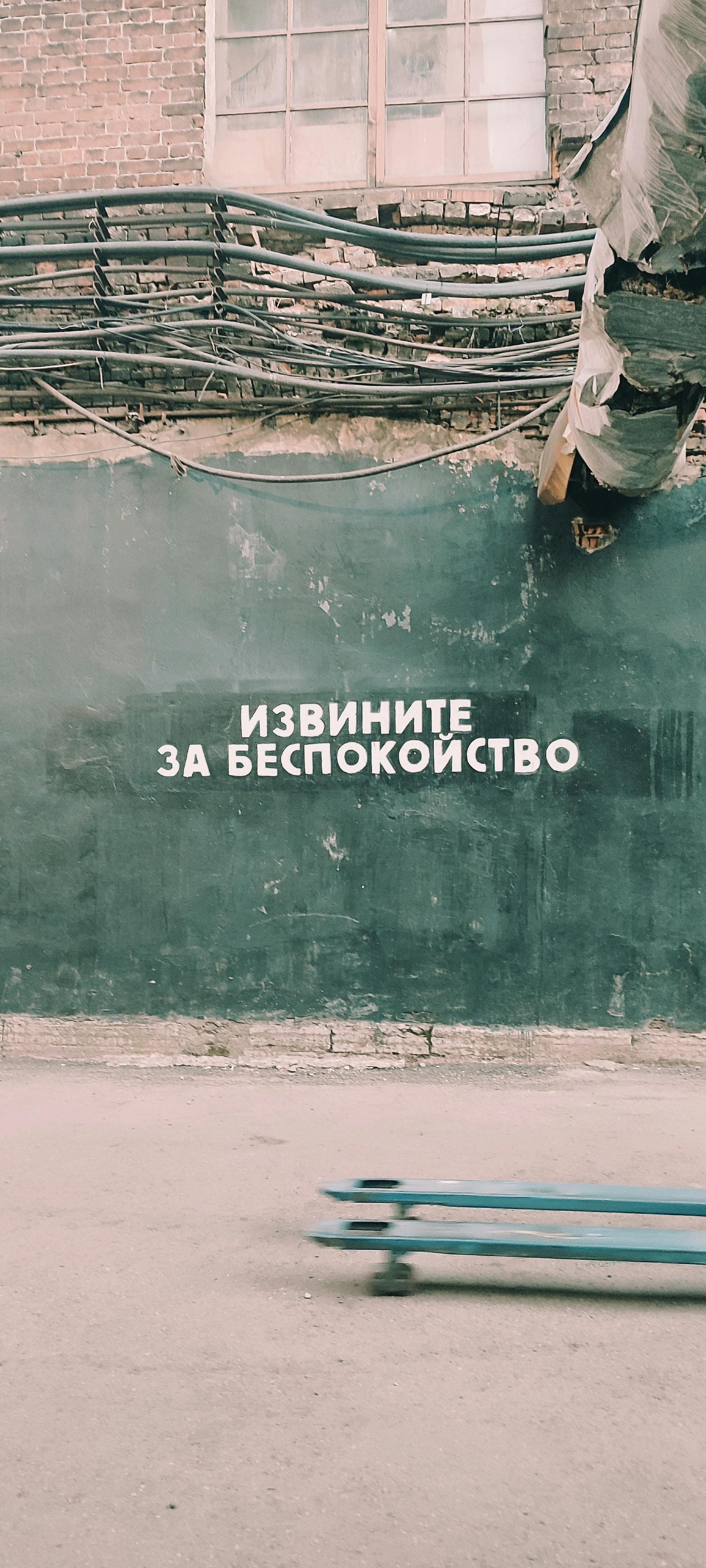 Street scene featuring wall art, exposed wires, and Cyrillic text in an industrial setting.