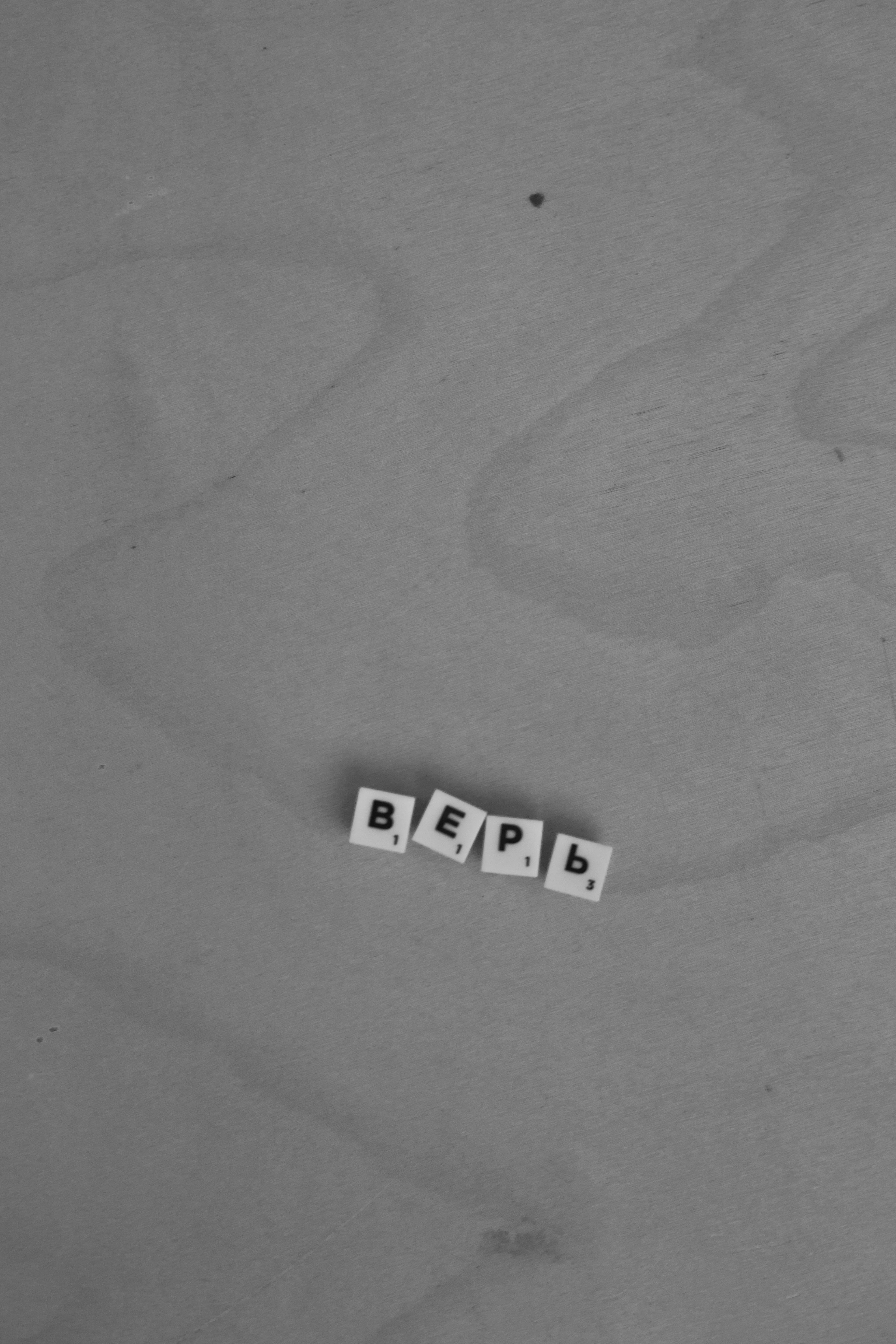 Black and white photo of Cyrillic letters forming 'верь' on a wooden surface.