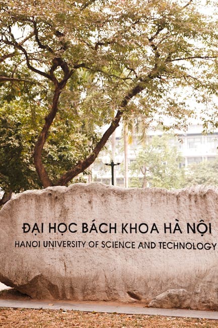 Stone sign of Hanoi University of Science and Technology amidst trees, capturing serene campus atmosphere.
