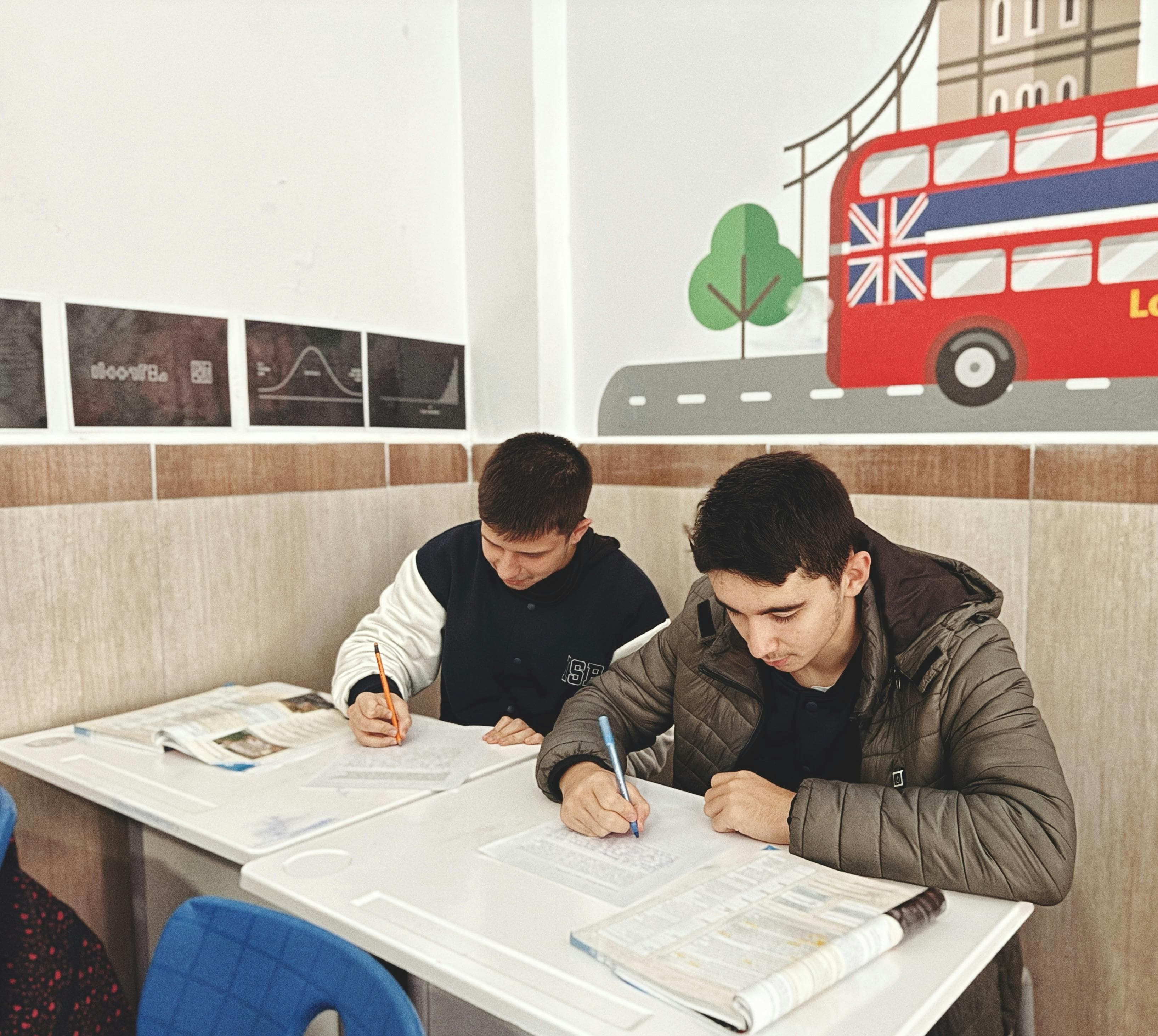 Londra temalı bir sınıf ortamında ders materyallerine odaklanmış iki öğrenci.