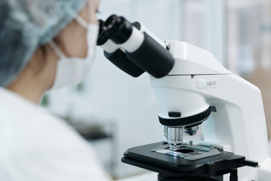 Scientist using a microscope in a laboratory environment. Focus on research and analysis.