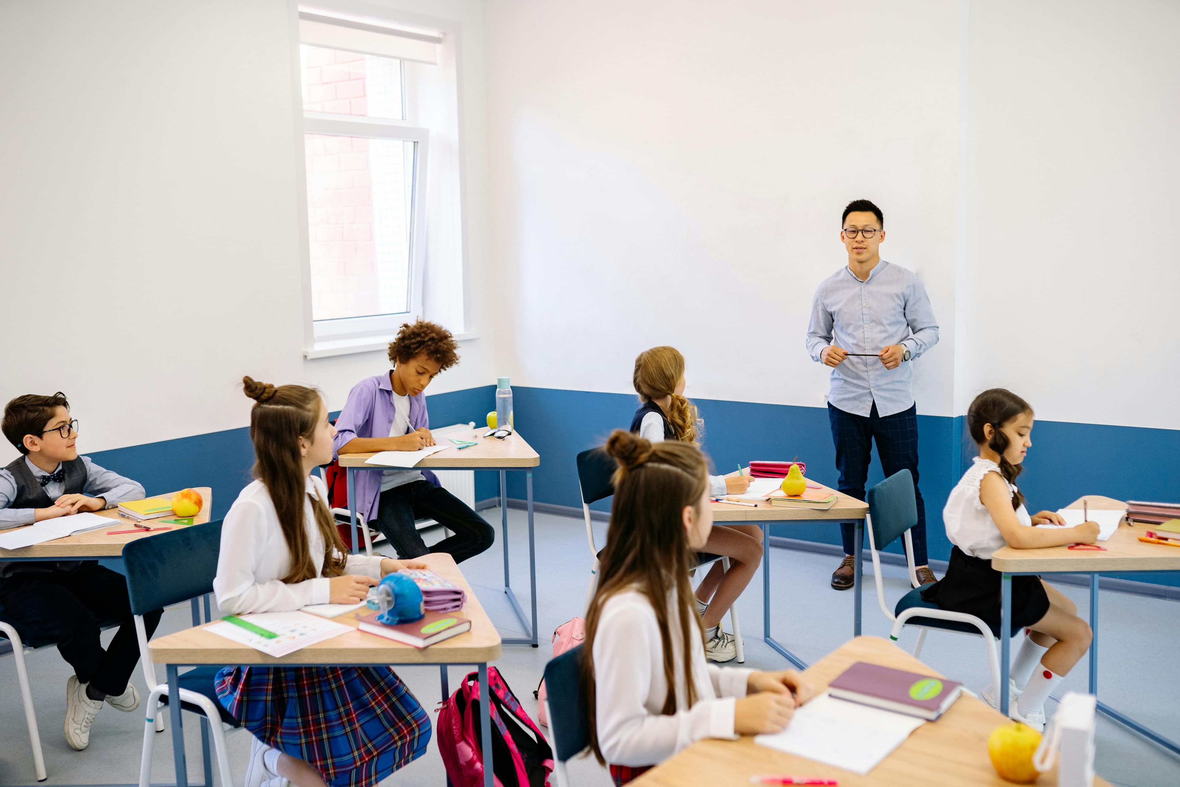 老师在现代化教室中指导一群多元背景的小学生。