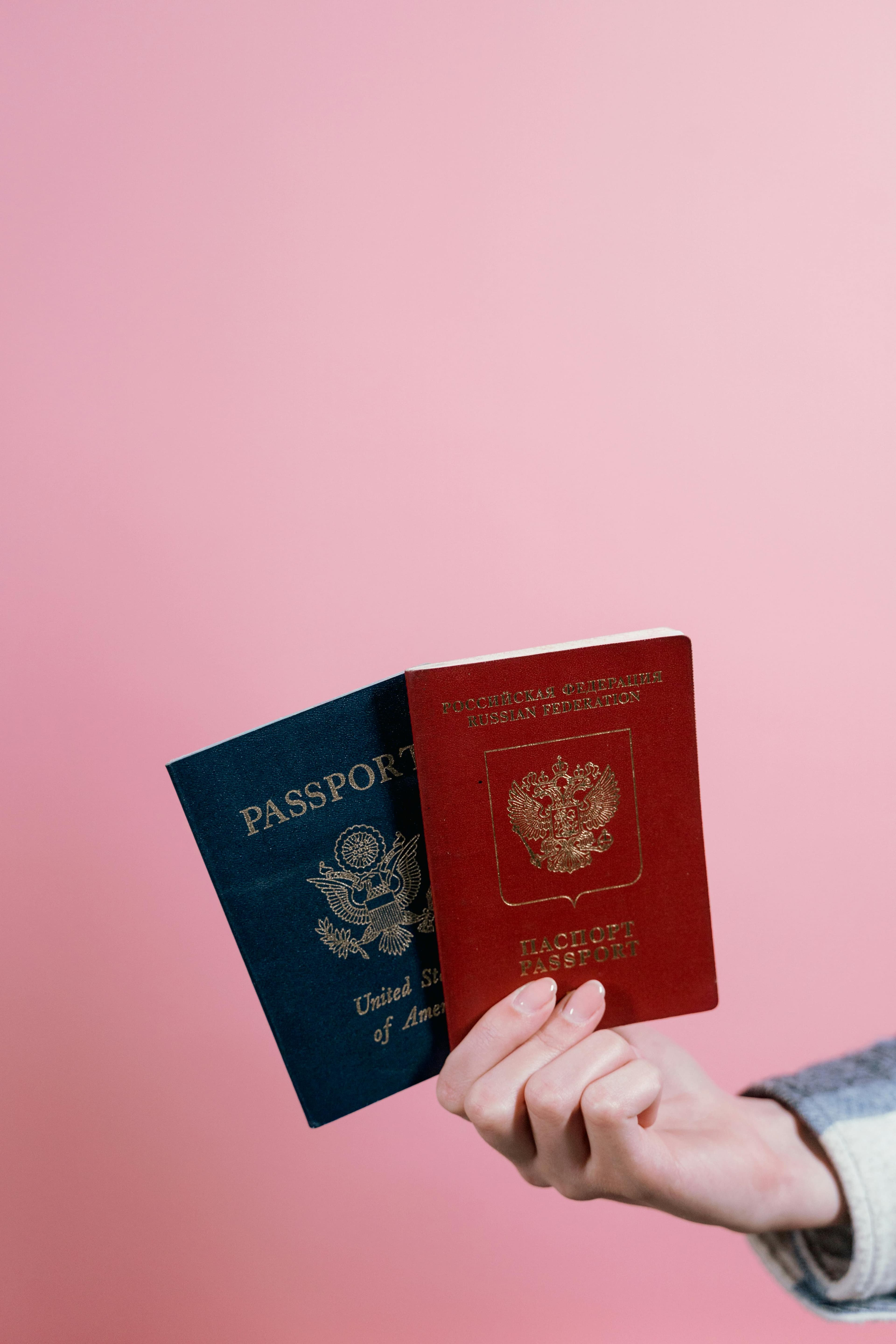 Улыбающаяся женщина с паспортом в руке показывает большой палец вверх на желтом фоне.
