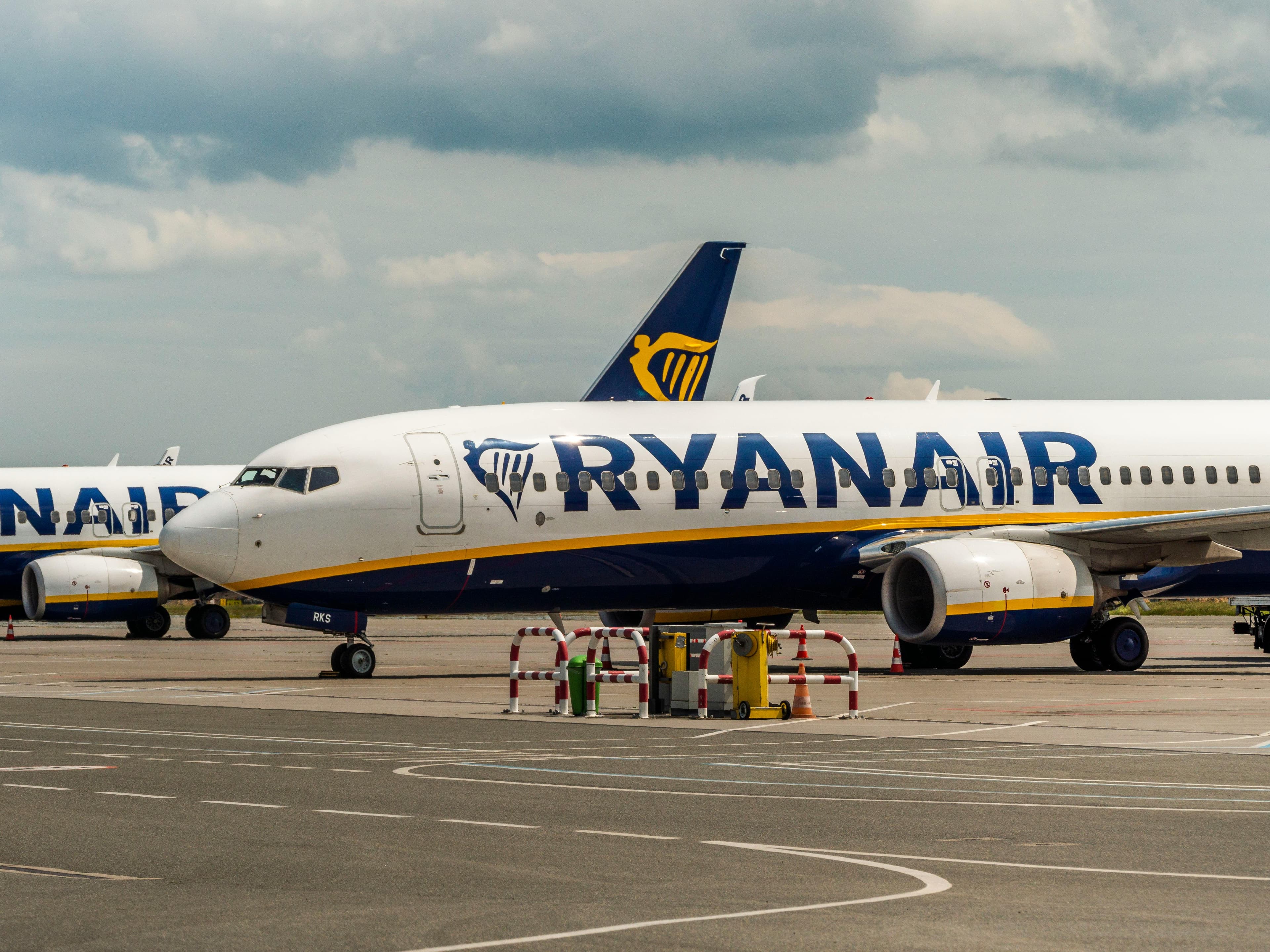 A Ryanair aircraft parked on the airport tarmac during the day under cloudy skies.