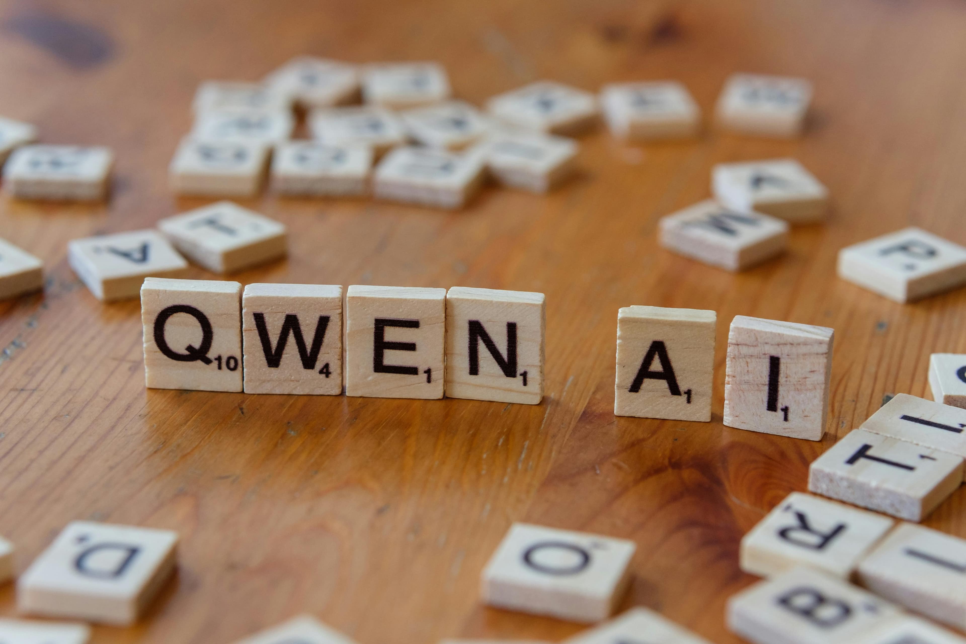 Ahşap bir yüzeyde 'Qwen AI' yazacak şekilde dizilmiş scrabble benzeri harfler, teknoloji kavramlarını tasvir ediyor.