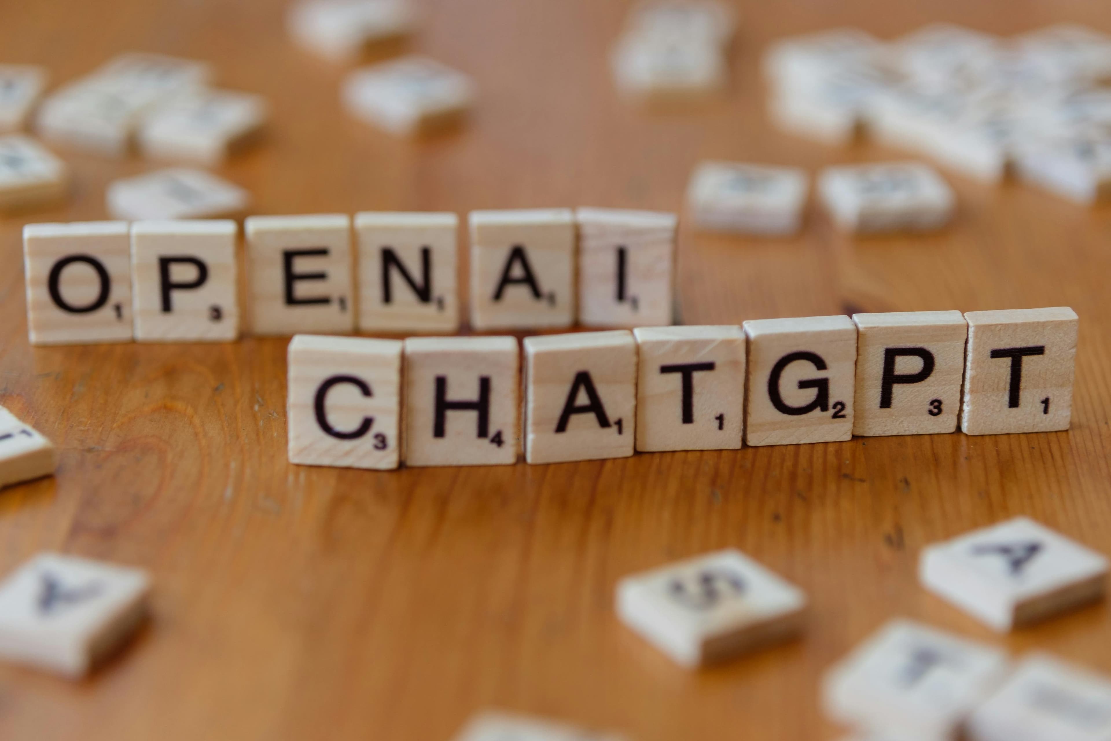 حروف چوبی که عبارت 'OPENAI CHATGPT' را روی یک سطح چوبی می‌سازند، تصویر متمرکز.