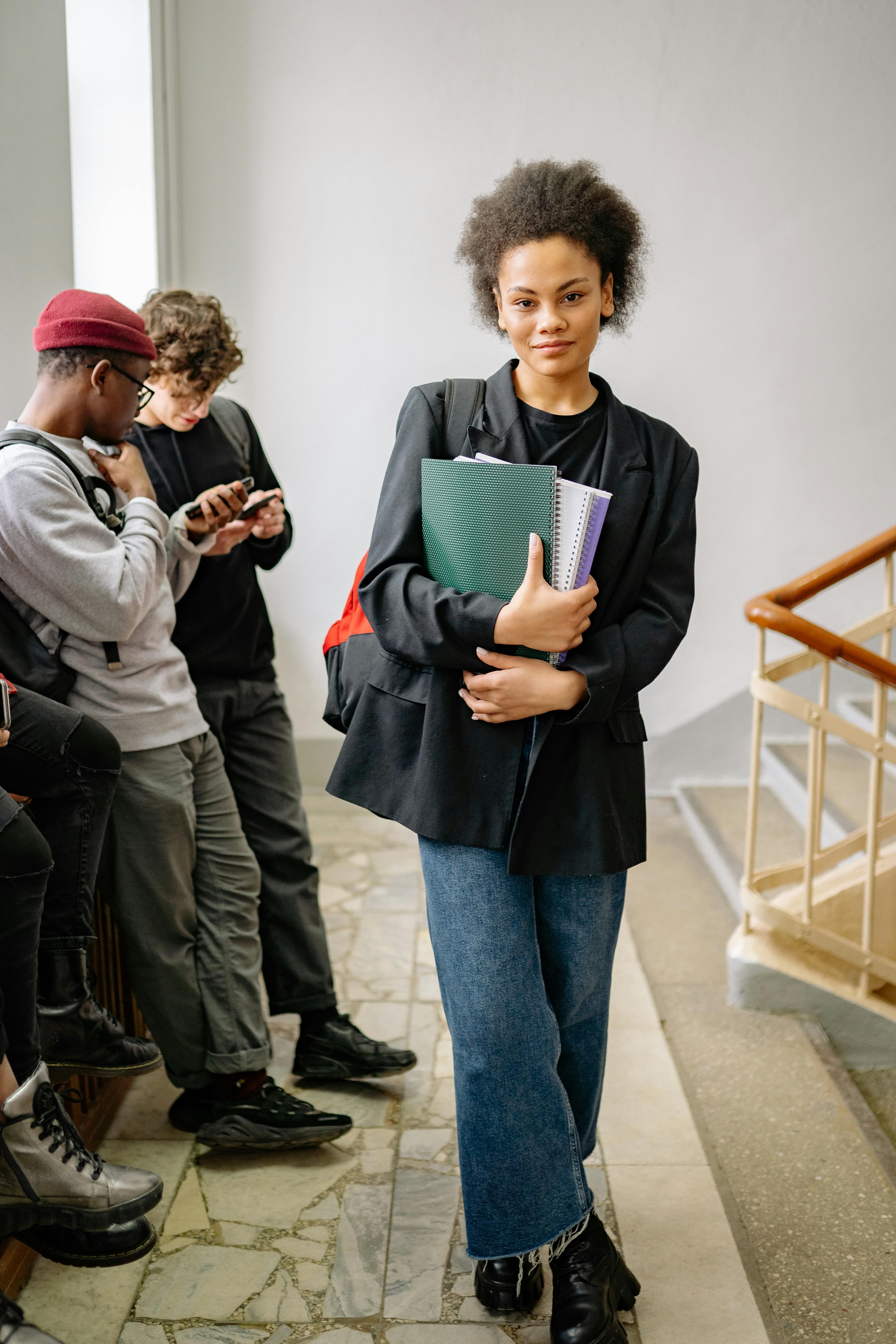 A stylish student confidently carrying books, showcasing college life in an educational setting.