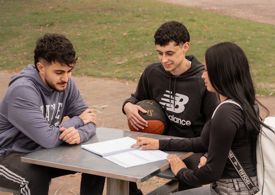Three young adults studying outdoors, engaging in a casual study session in Montevideo, Uruguay.