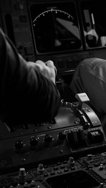 Monochrome photo of a pilot's hand adjusting controls in an aircraft cockpit, highlighting aviation technology.