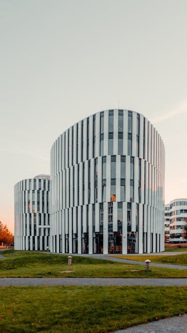 Contemporary office buildings with glass facades in a park setting at sunset.