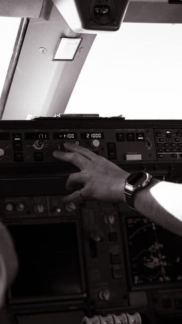 Close-up of a pilot adjusting aircraft controls inside a cockpit.