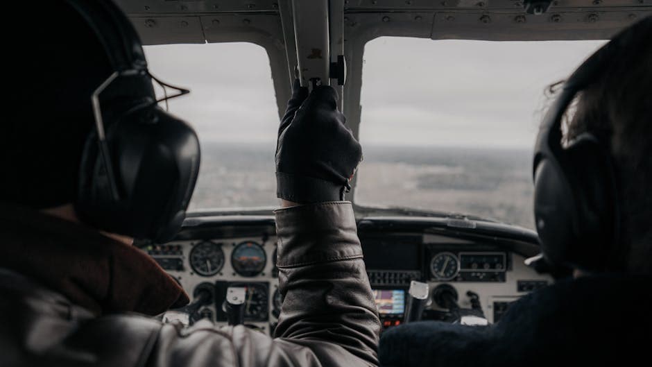 Two pilots operating a small aircraft from the cockpit with clear dashboard view.