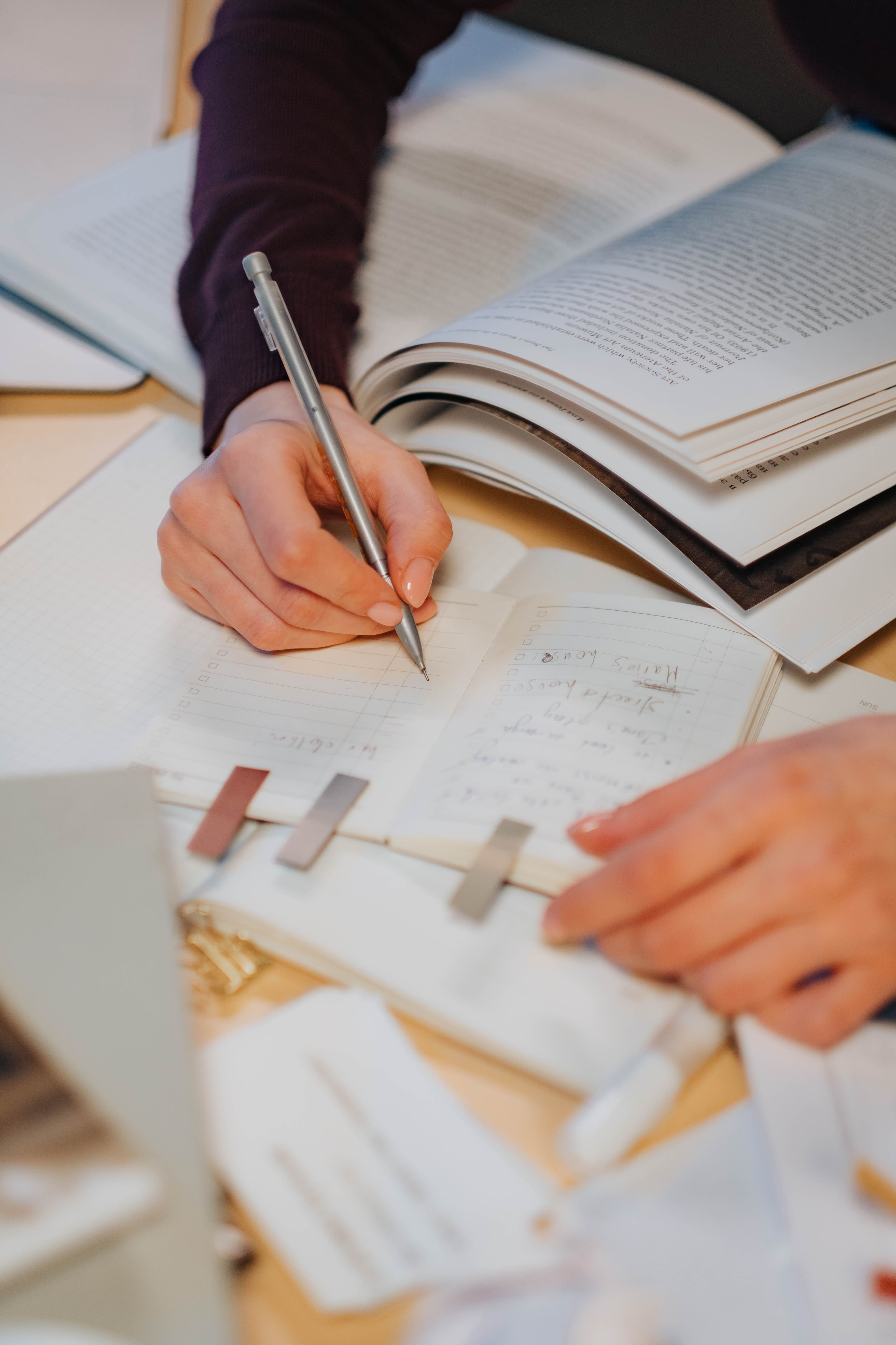 Gros plan d'un homme écrivant des notes sur un cahier à l'aide d'un ordinateur portable à l'intérieur.