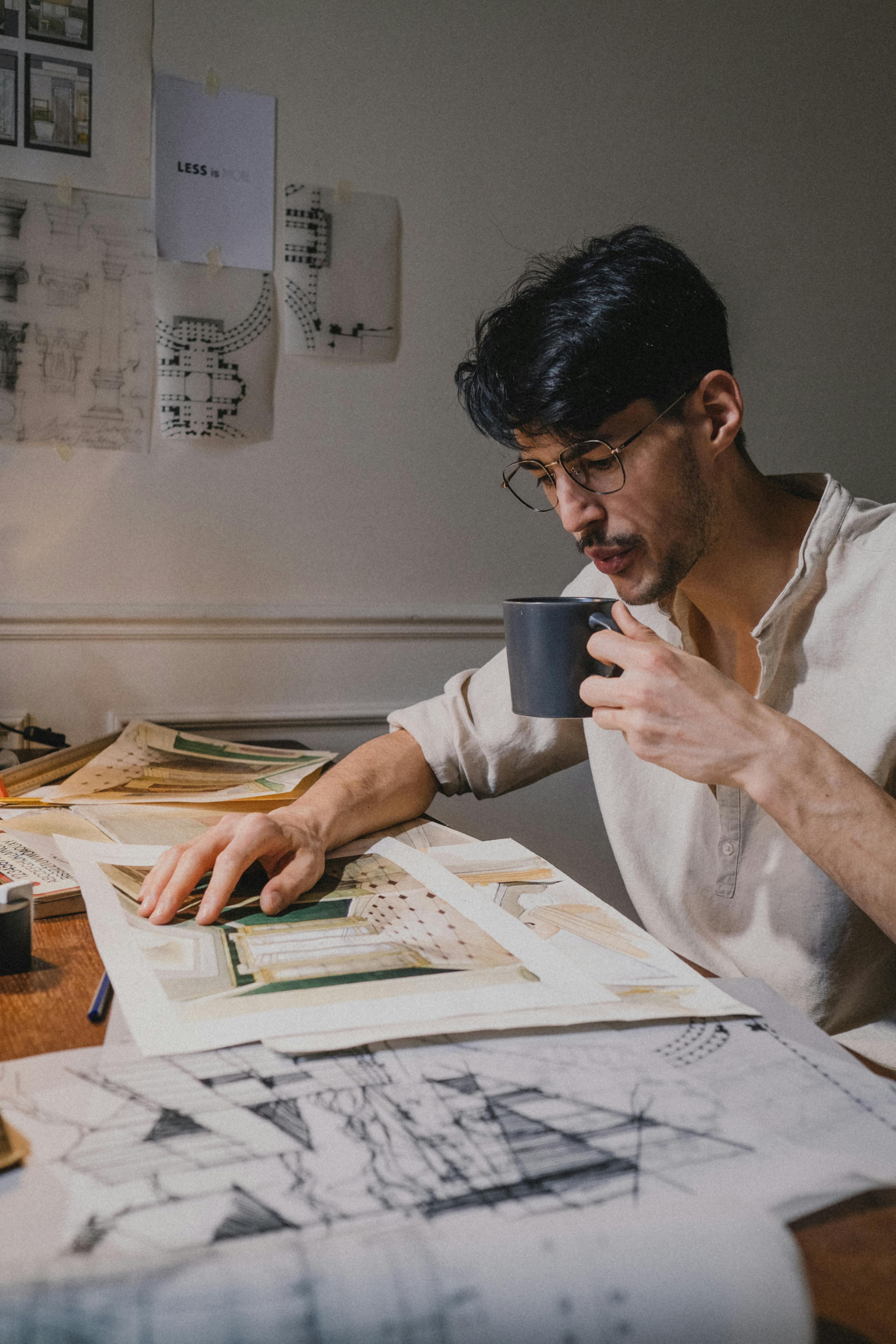شاب في مكتبة يعمل على تصميم على مكتب بتركيز واهتمام. مثالي للموضوعات التعليمية والإبداعية.