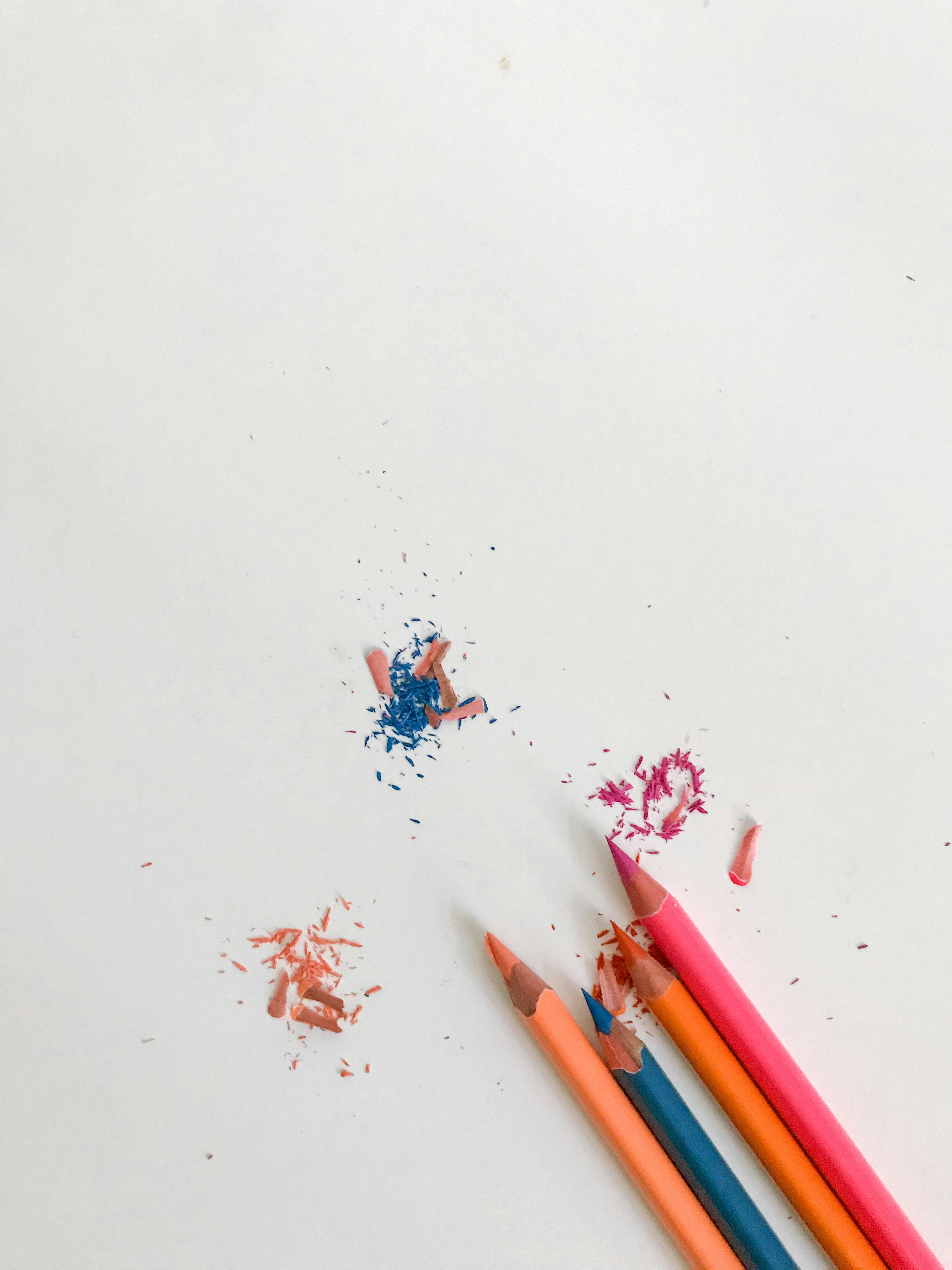Top view of sharp bright graphite pencils with shavings placed on white table